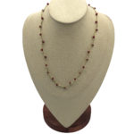 Collana artigianale dorata con piccole perline rosso bordeaux distribuite lungo la catena, gioiello elegante e minimal.
