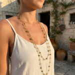 Collana lunga artigianale Doralie in colore oro e ambra su modella in ambiente pugliese