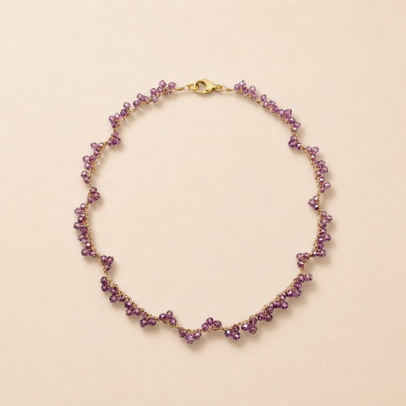 : Collana Iride Doralie in ametista naturale e filo dorato su sfondo chiaro.