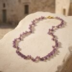 Dettaglio ravvicinato delle gemme in ametista sfaccettata e dell'intreccio dorato fatto a mano della collana Iride.
