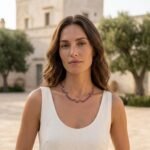 Modella con vestito in lino chiaro che indossa la collana Iride in ametista Doralie in una masseria pugliese.
