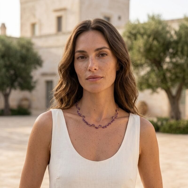 Modella con vestito in lino chiaro che indossa la collana Iride in ametista Doralie in una masseria pugliese.